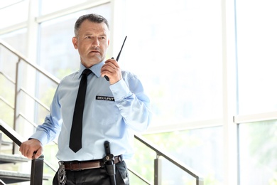 Photo of Male security guard using portable radio transmitter indoors