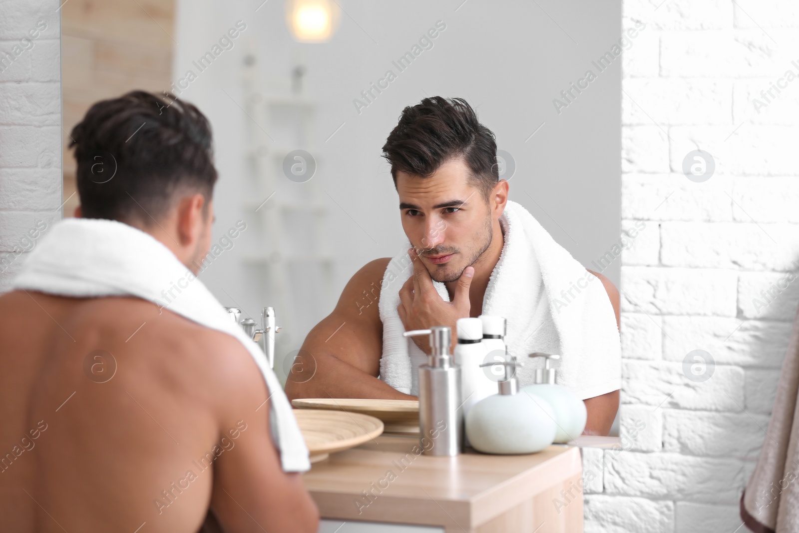 Photo of Young man with stubble ready for shaving near mirror in bathroom