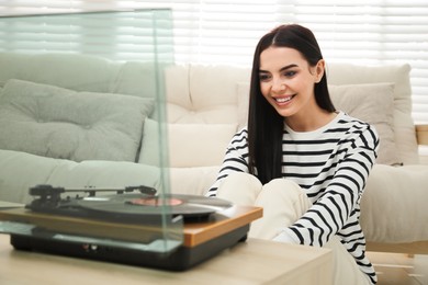 Photo of Woman listening to music with turntable at home