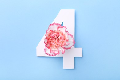 Photo of Paper number 4 and beautiful flower on light blue background, top view
