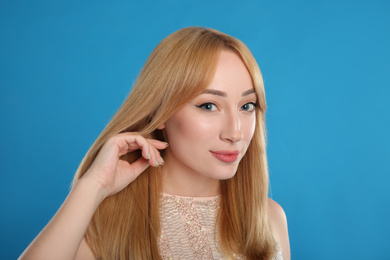 Portrait of beautiful young woman with blonde hair on blue background