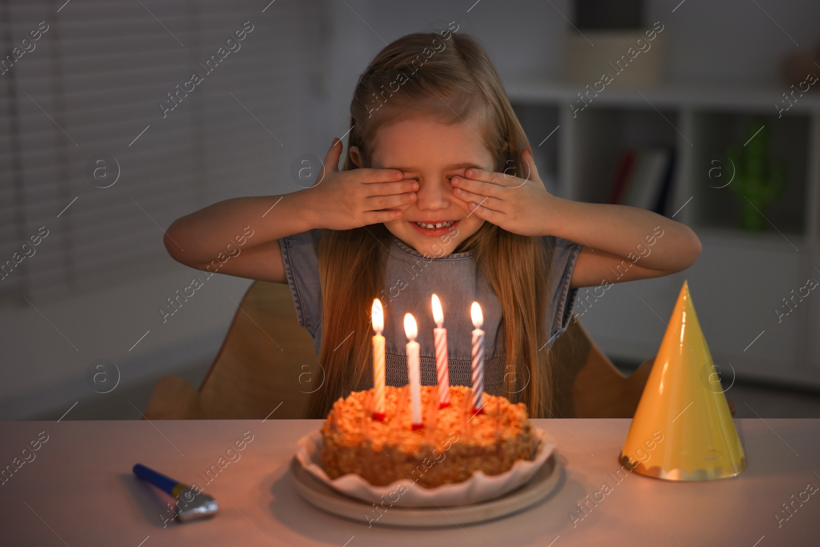 Photo of Cute girl with birthday cake at table indoors