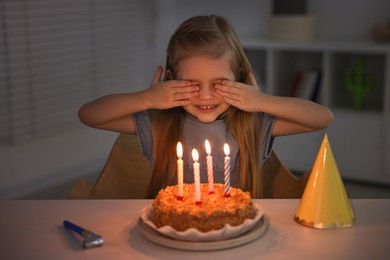 Cute girl with birthday cake at table indoors