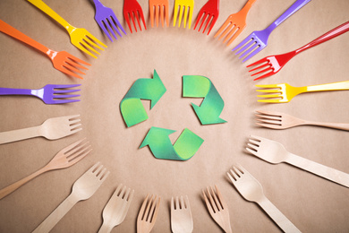Photo of Recycling symbol, plastic and wooden forks on beige background, flat lay