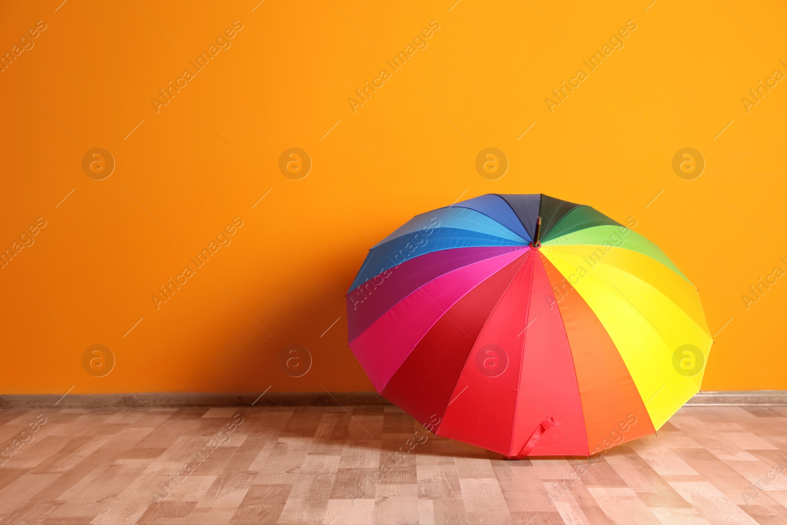 Photo of Beautiful open umbrella on floor near color wall with space for design