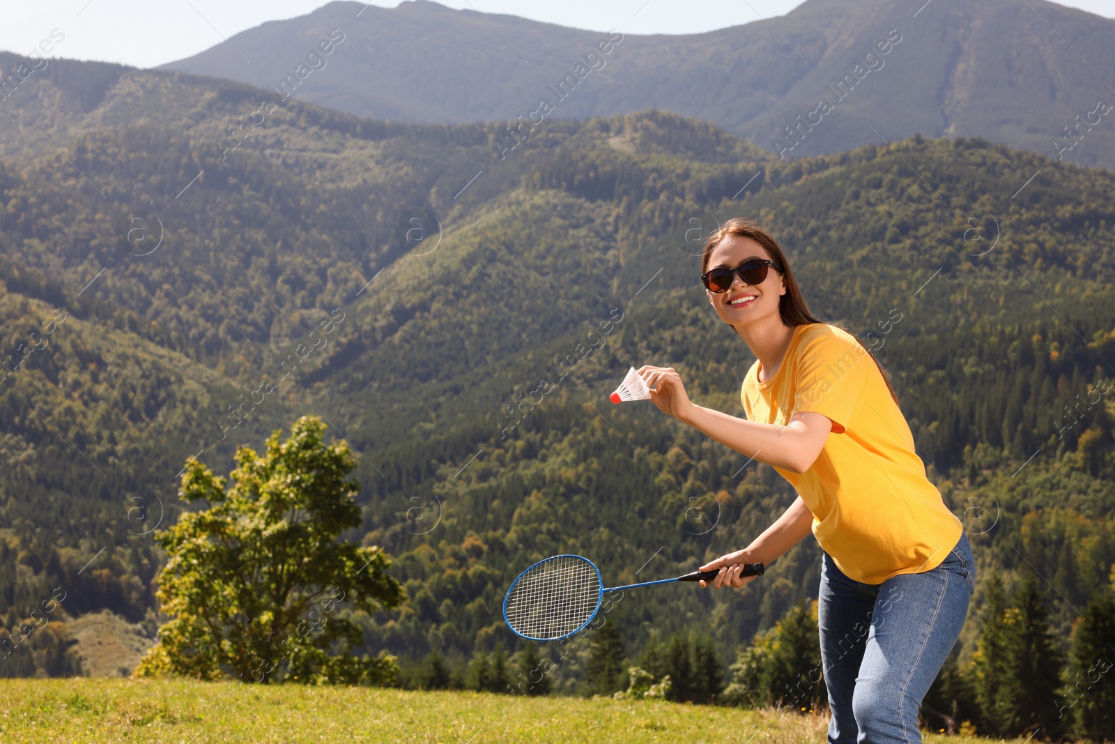 Photo of Woman playing badminton in mountains on sunny day. Space for text