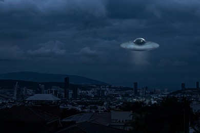 Image of Alien spaceship flying over city in evening. UFO, extraterrestrial visitors