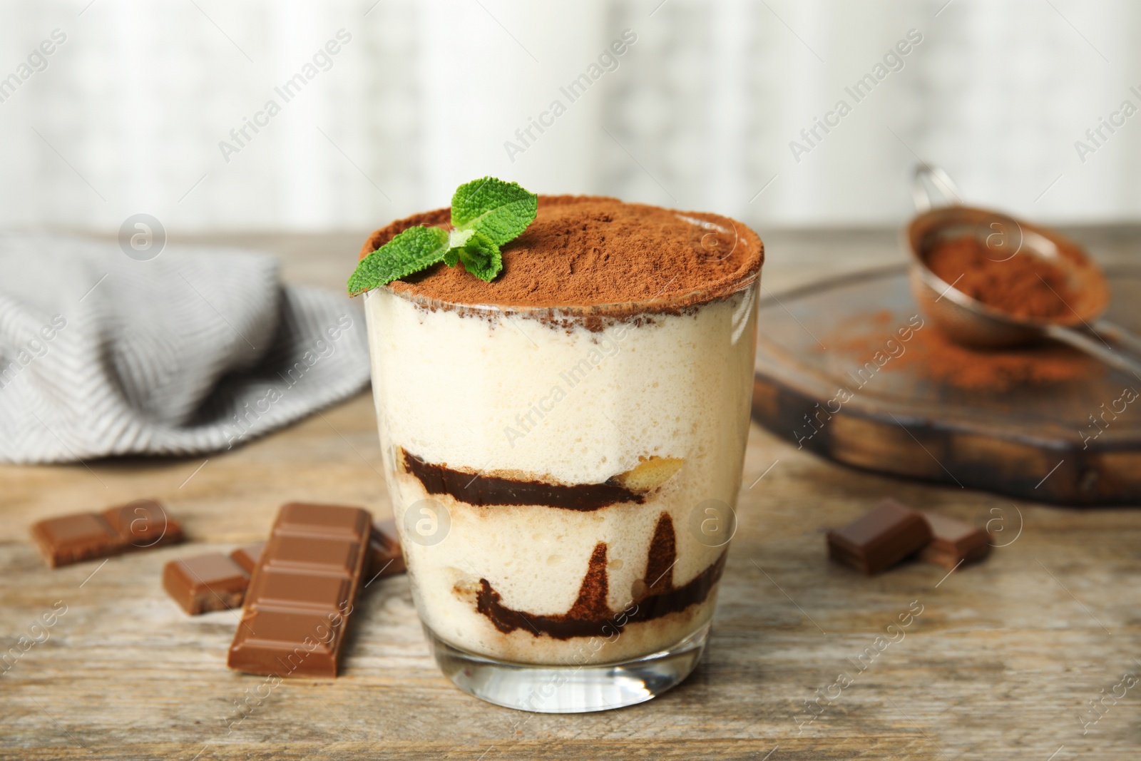 Photo of Glass of tiramisu cake and chocolate on wooden table