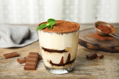 Photo of Glass of tiramisu cake and chocolate on wooden table