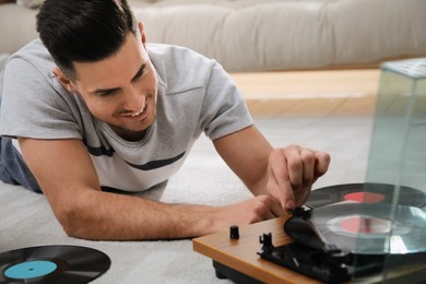 Photo of Happy man using turntable while lying on floor at home