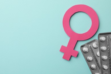 Photo of Female gender sign, blisters of pills and space for text on turquoise background, flat lay. Women's health concept
