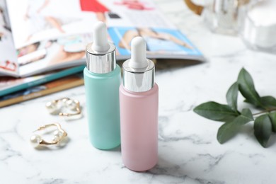 Photo of Bottles of cosmetic products on white marble table