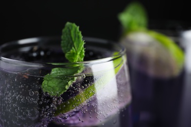 Photo of Delicious blackberry lemonade made with soda water on dark background, closeup