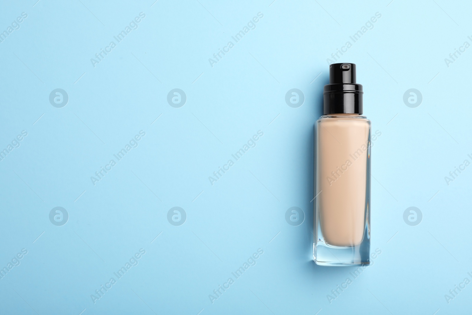 Photo of Bottle of skin foundation and space for text on color background, top view