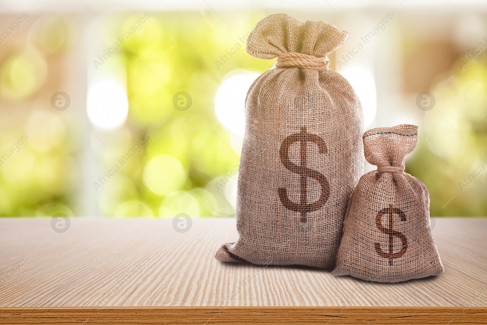 Image of Burlap bags with dollar signs on wooden table indoors. Space for text