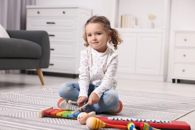 Little girl playing toy xylophone at home