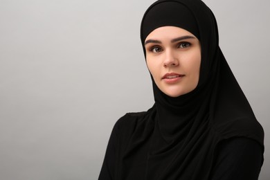 Portrait of Muslim woman in hijab on light gray background, space for text