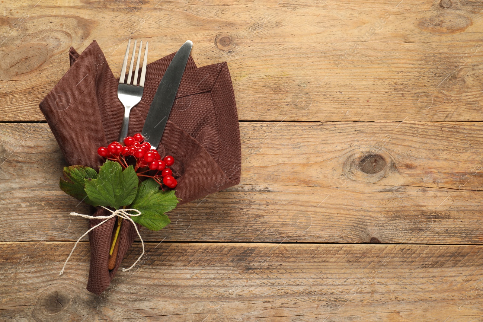 Photo of Autumn table setting. Cutlery, napkin and viburnum berries on wooden background, top view with space for text