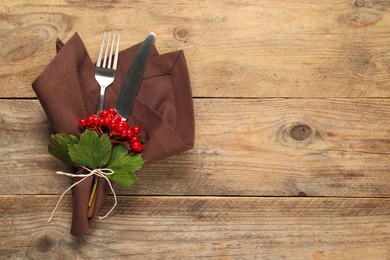 Photo of Autumn table setting. Cutlery, napkin and viburnum berries on wooden background, top view with space for text