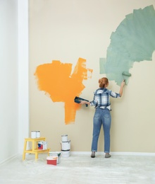 Woman painting wall indoors, space for text. Home repair