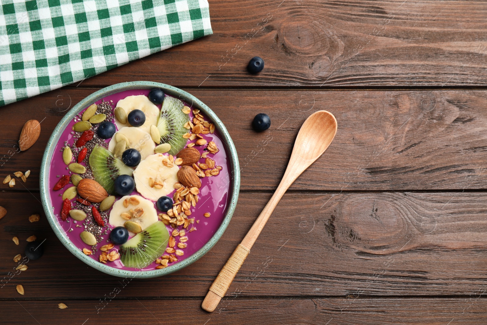 Photo of Delicious acai smoothie with granola and fruits on wooden table, flat lay. Space for text