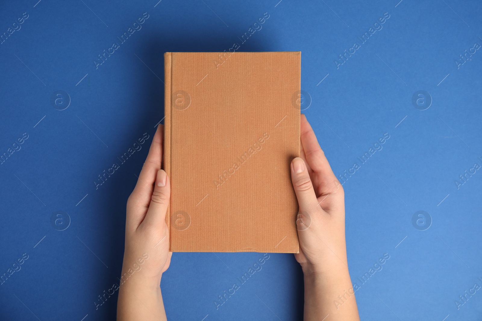 Photo of Woman with book on blue background, top view. Space for design