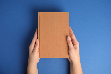 Woman with book on blue background, top view. Space for design