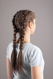 Woman with braided hair on grey background, back view