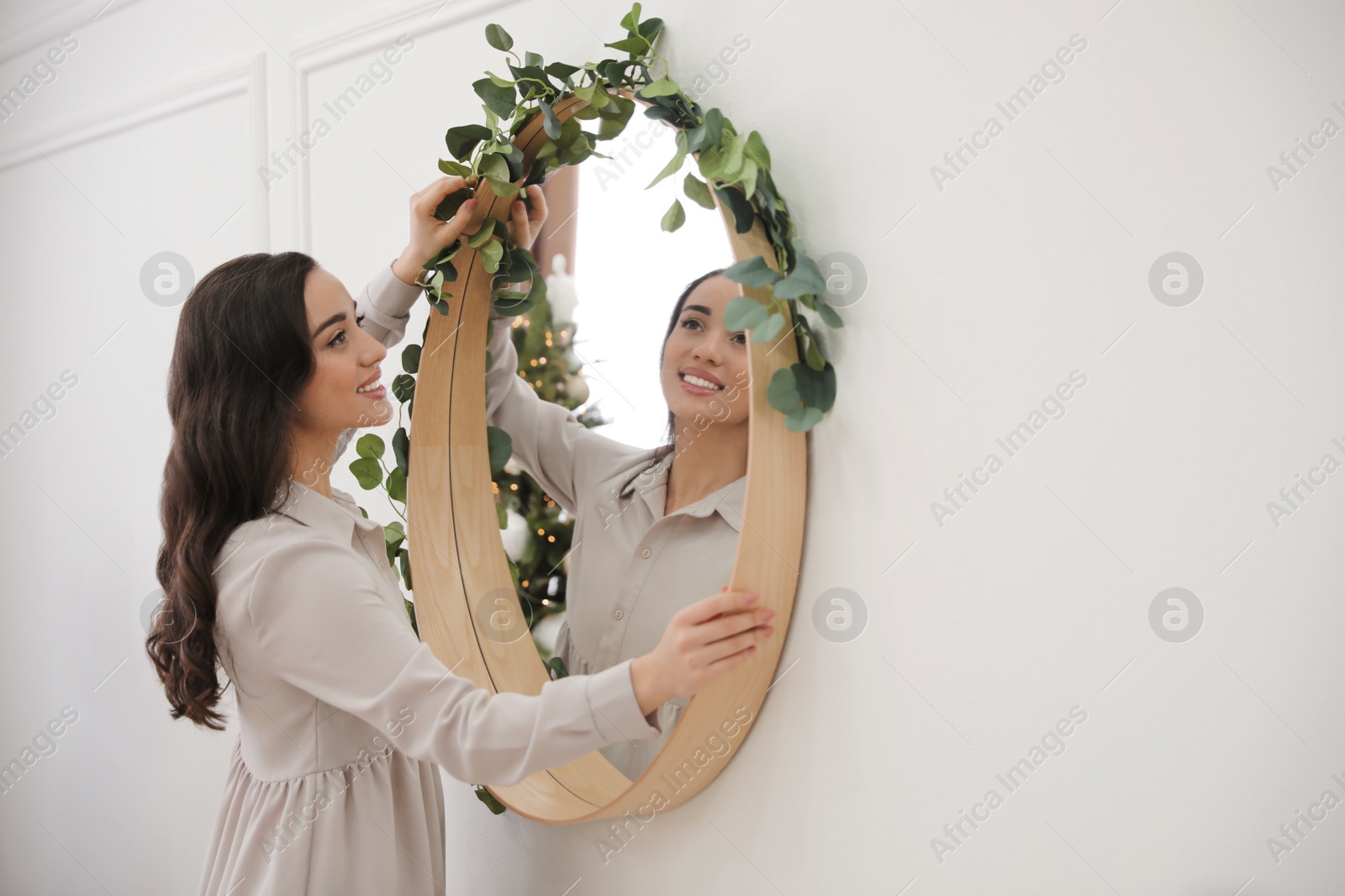 Photo of Woman decorating mirror with eucalyptus branches at home