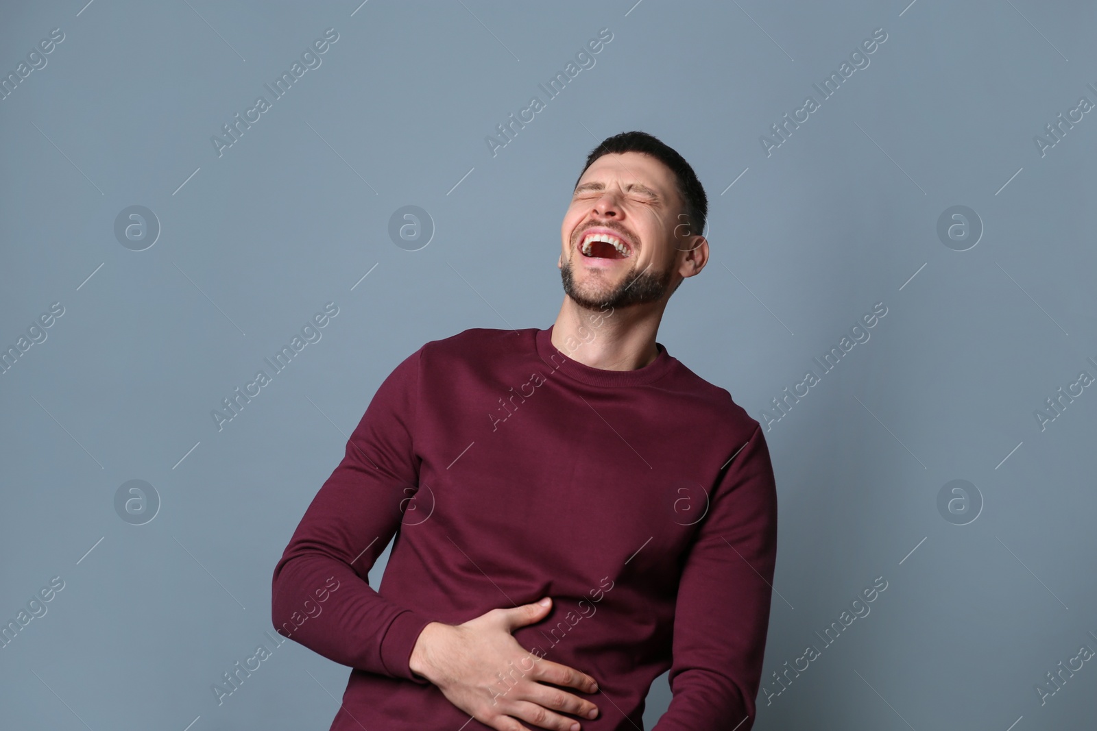 Photo of Handsome man laughing on grey background. Funny joke