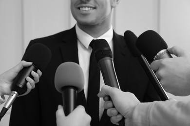 Image of Businessman giving interview to journalists indoors, closeup. Black and white effect