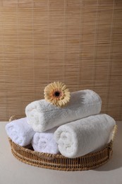 Rolled terry towels and flower on white table indoors, space for text