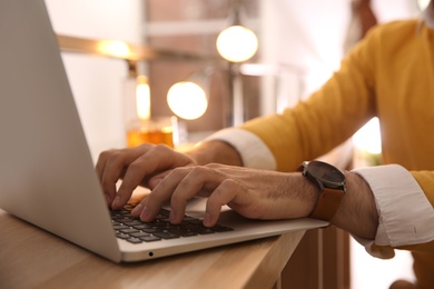 Man working with laptop at table in cafe, closeup