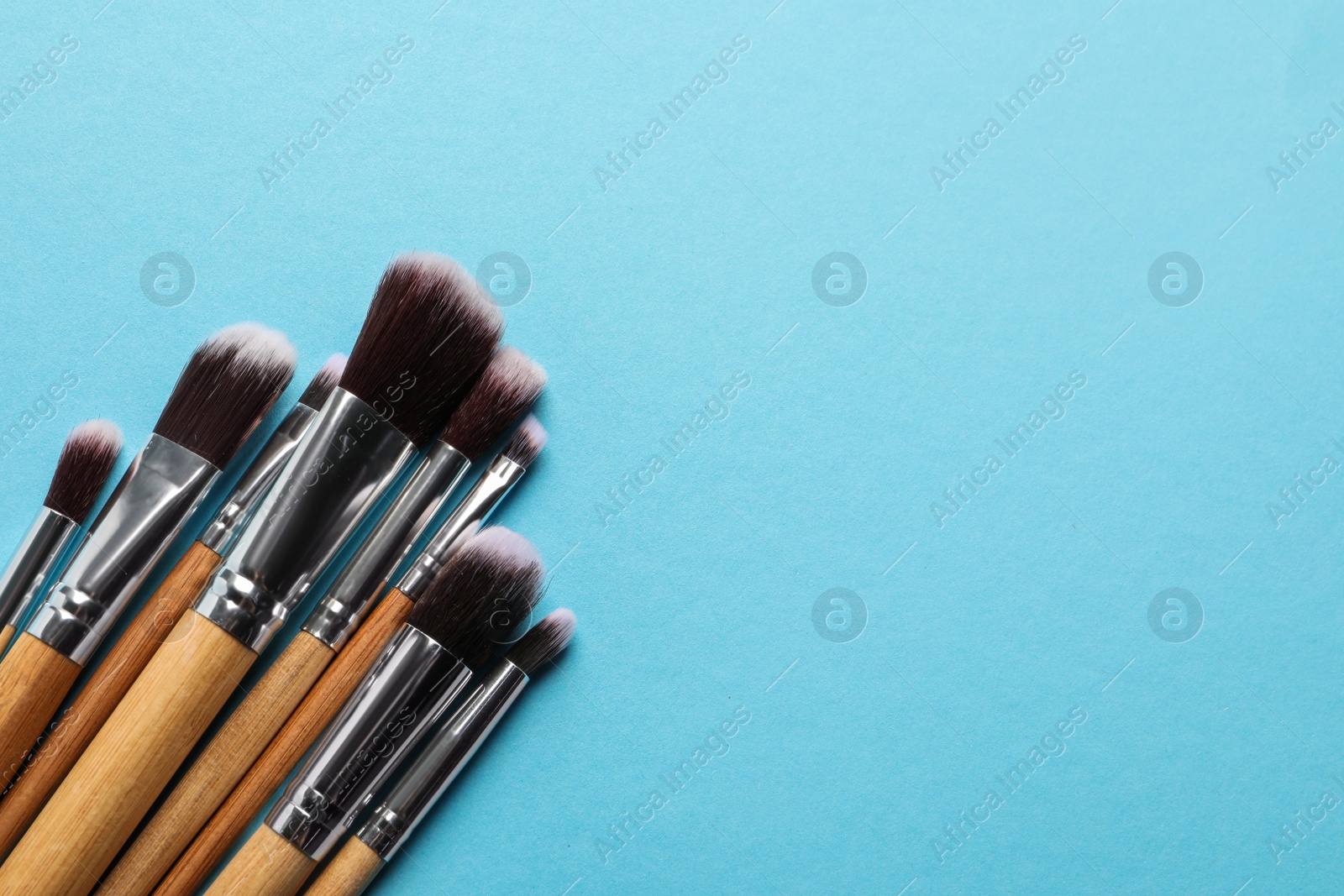 Photo of Different makeup brushes on light blue background, flat lay. Space for text