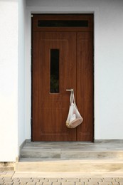 Helping neighbours. Net bag of products hanging on door outdoors