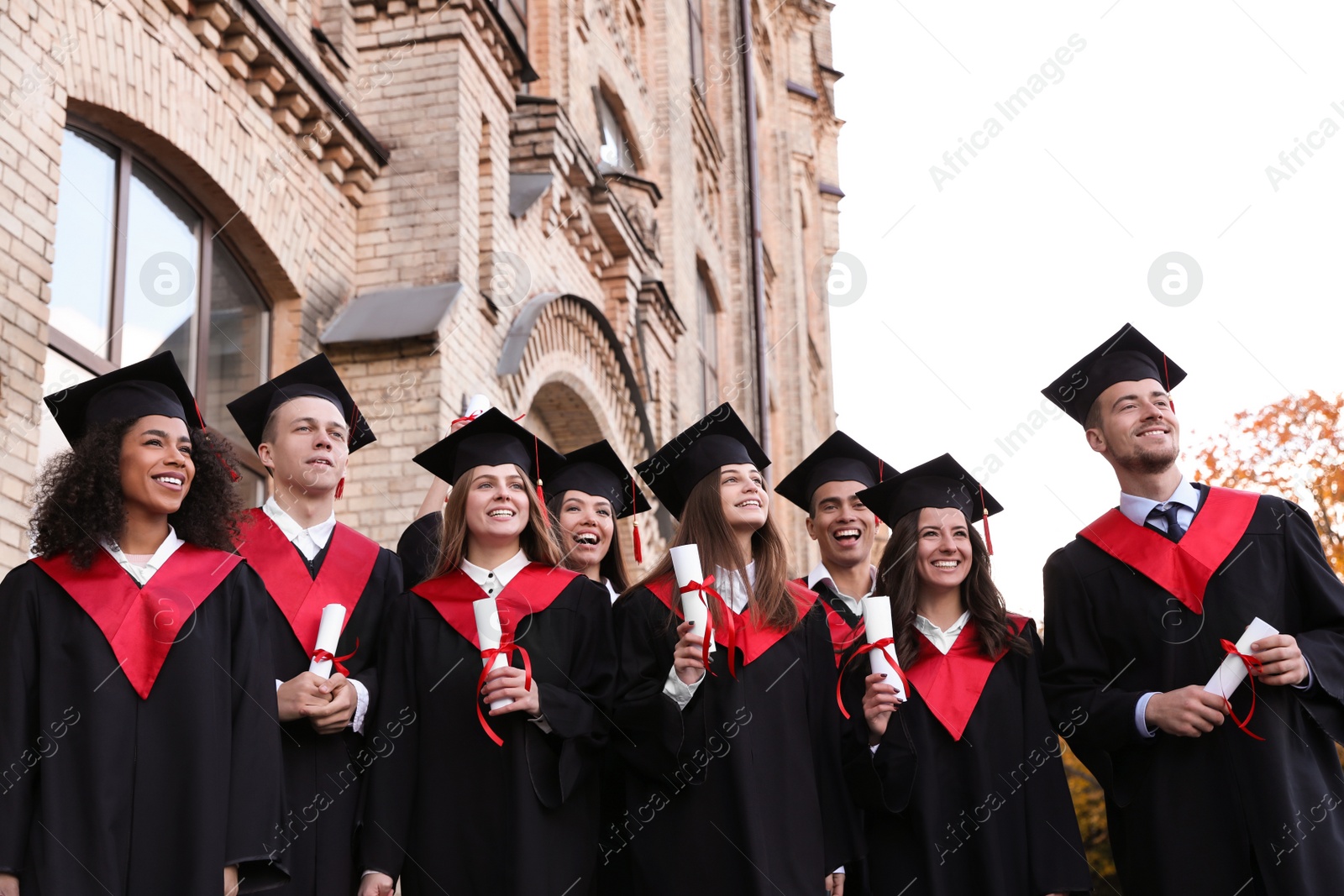 Photo of Happy students with diplomas outdoors. Graduation ceremony