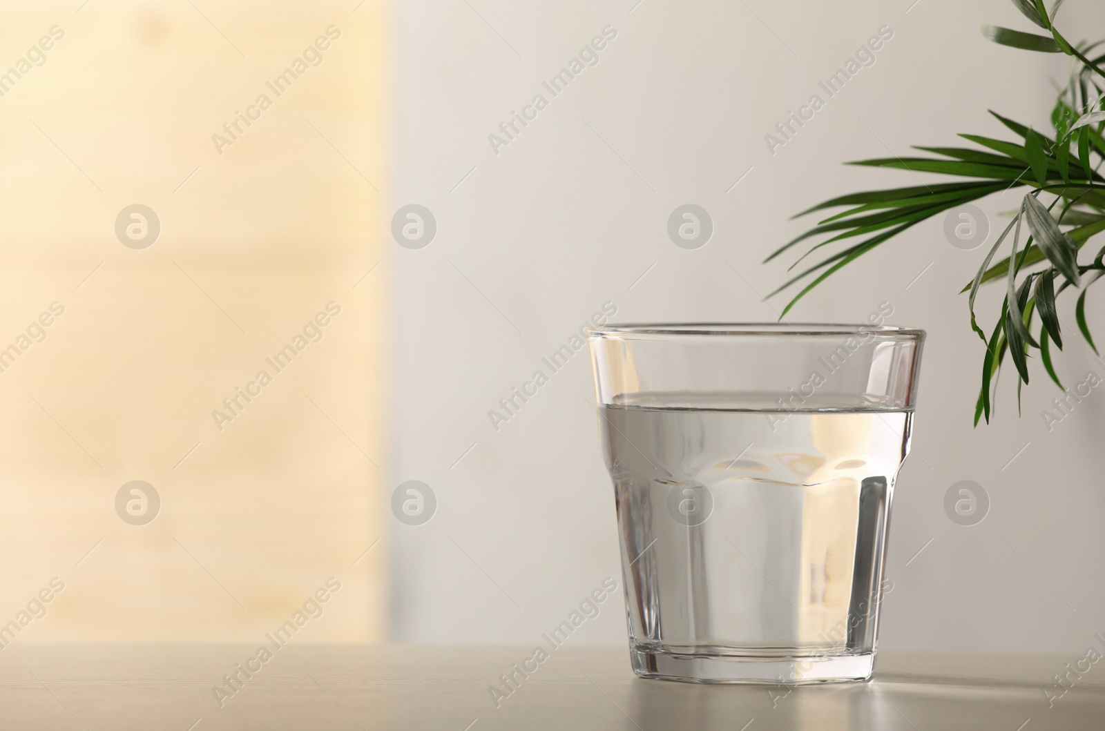 Photo of Glass of pure water on table against blurred background, space for text