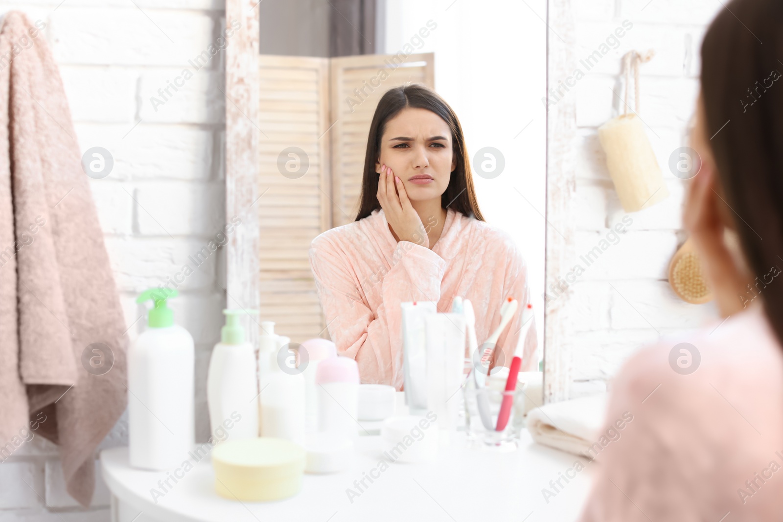 Photo of Young woman with sensitive teeth in bathroom