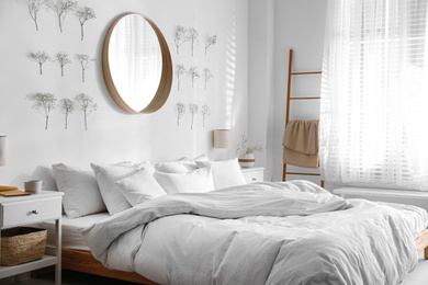 Modern bedroom interior with stylish round mirror