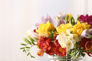 Photo of Beautiful bouquet of spring freesia flowers on light background, closeup. Space for text