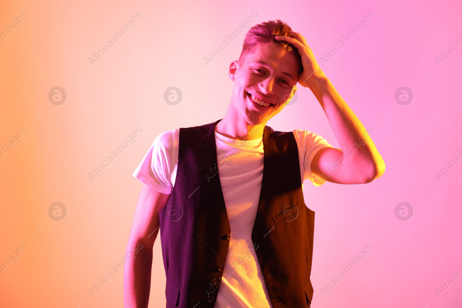 Photo of Stylish young man on pink background in neon lights