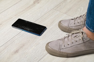 Woman near dropped smartphone on floor, closeup. Device repairing