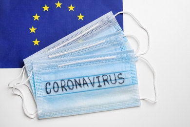 Protective masks and European Union flag on white background, flat lay. Coronavirus outbreak