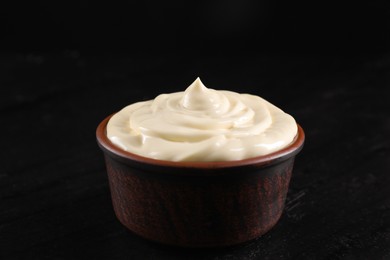 Photo of Fresh mayonnaise sauce in bowl on black table, closeup