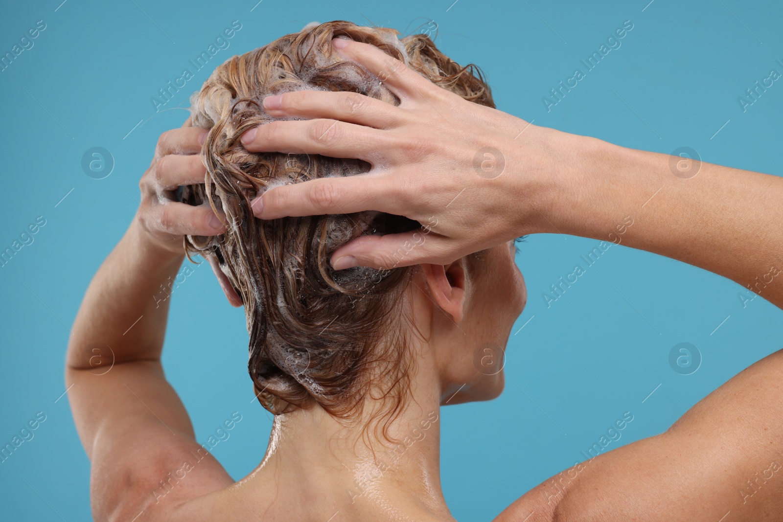 Photo of Woman washing hair on light blue background