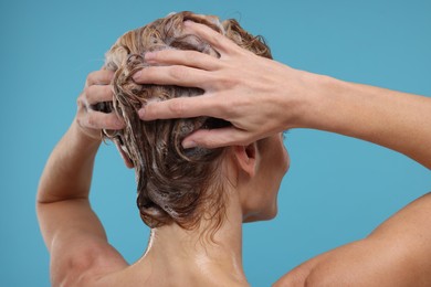 Photo of Woman washing hair on light blue background