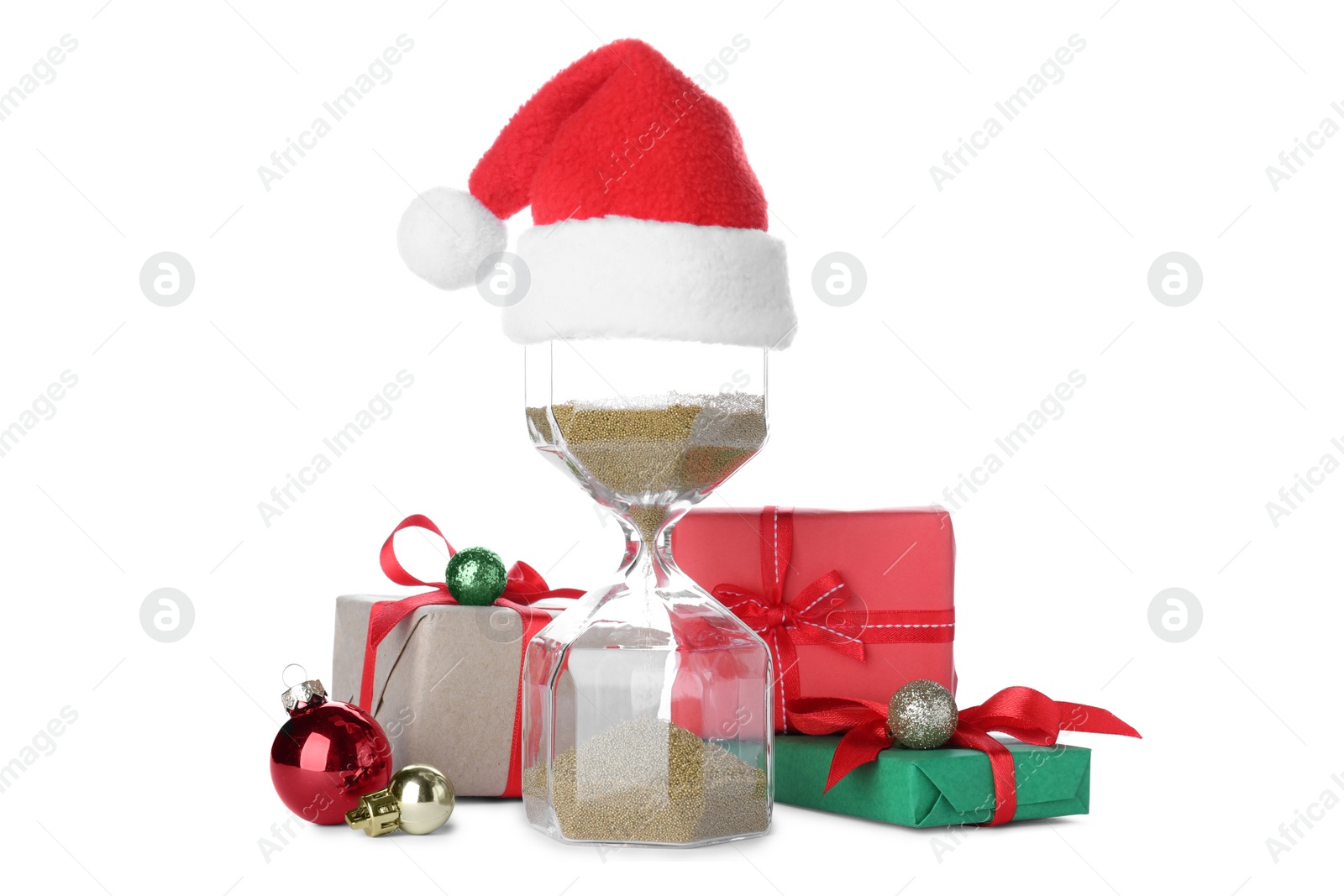 Photo of Hourglass with Santa hat and gifts on white background. Christmas countdown