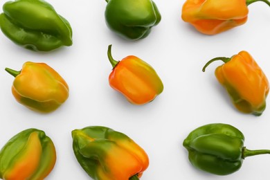 Different fresh raw hot chili peppers on white background, flat lay