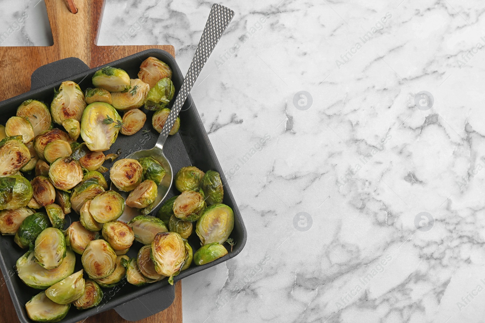 Photo of Delicious roasted brussels sprouts on white marble table, top view. Space for text