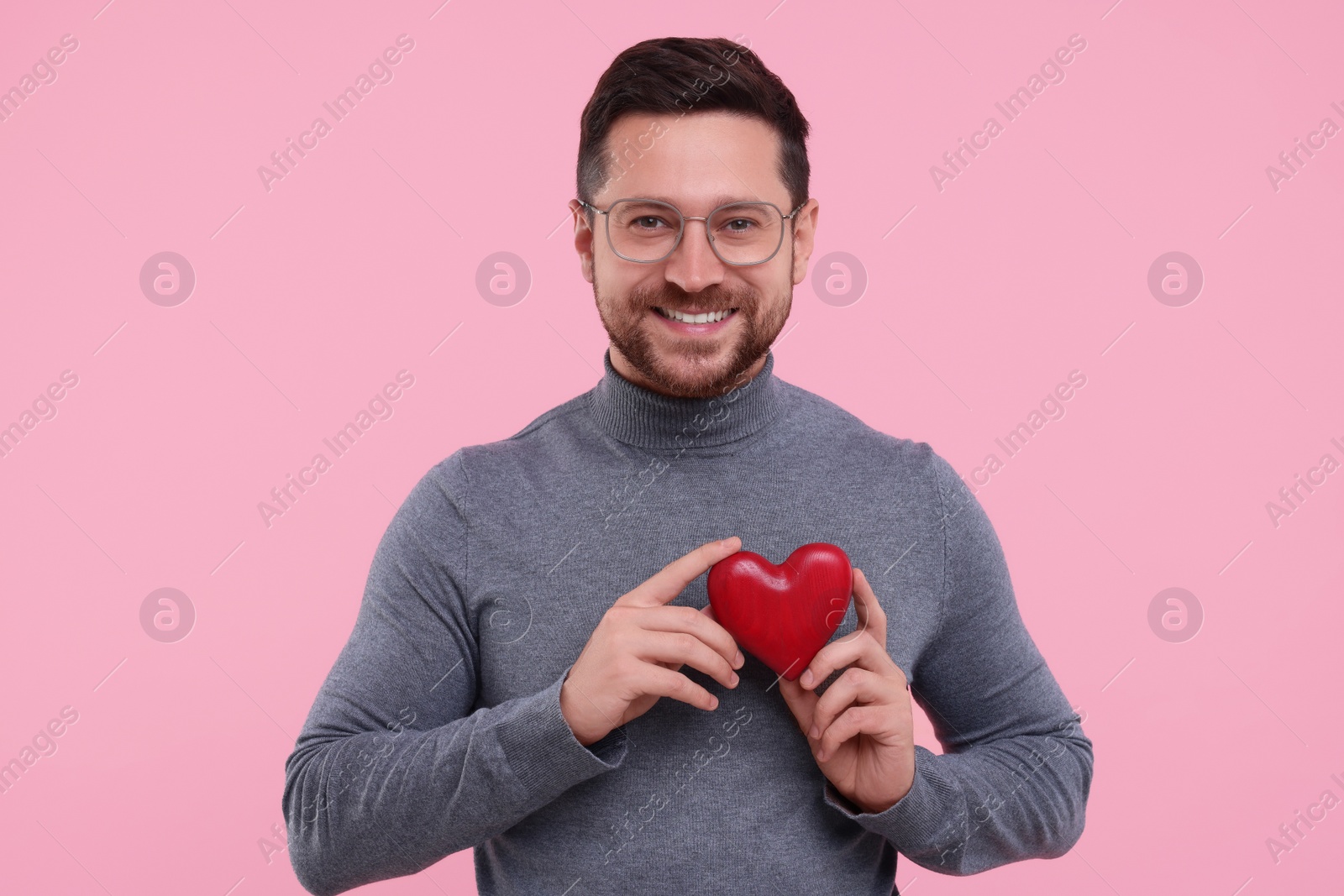 Photo of Happy man holding red heart on pink background
